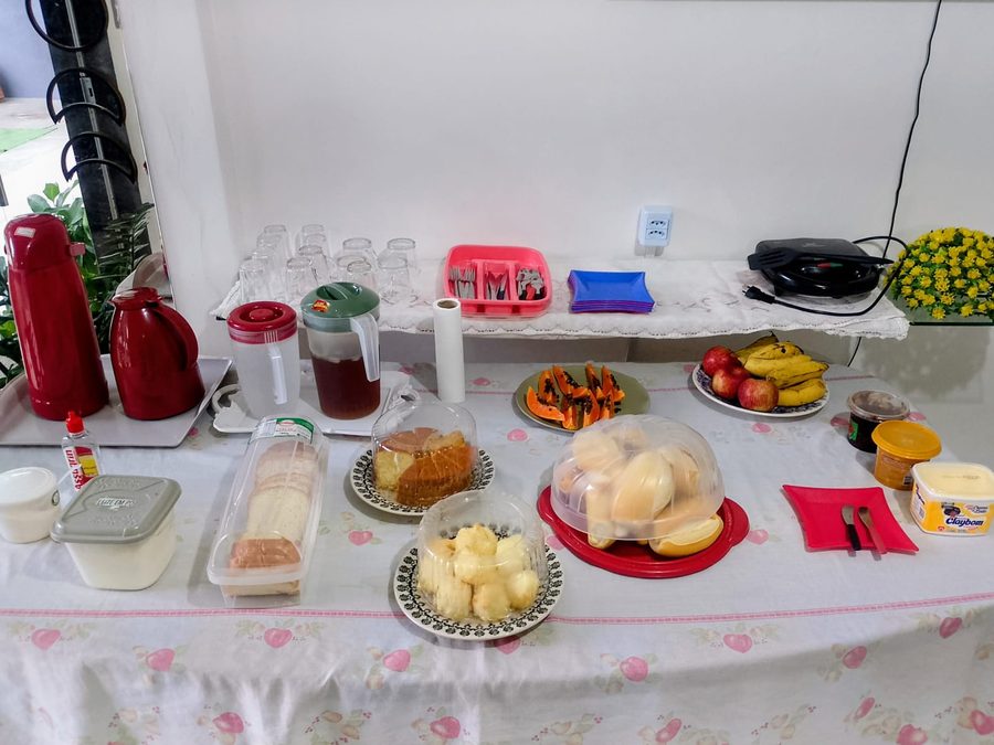Mesa do café da manhã com frutas, bolo, pães, frios e sucos